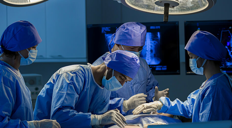 Surgical team operating in a hospital OR, where a line isolation monitor alarm can sound mid-procedure